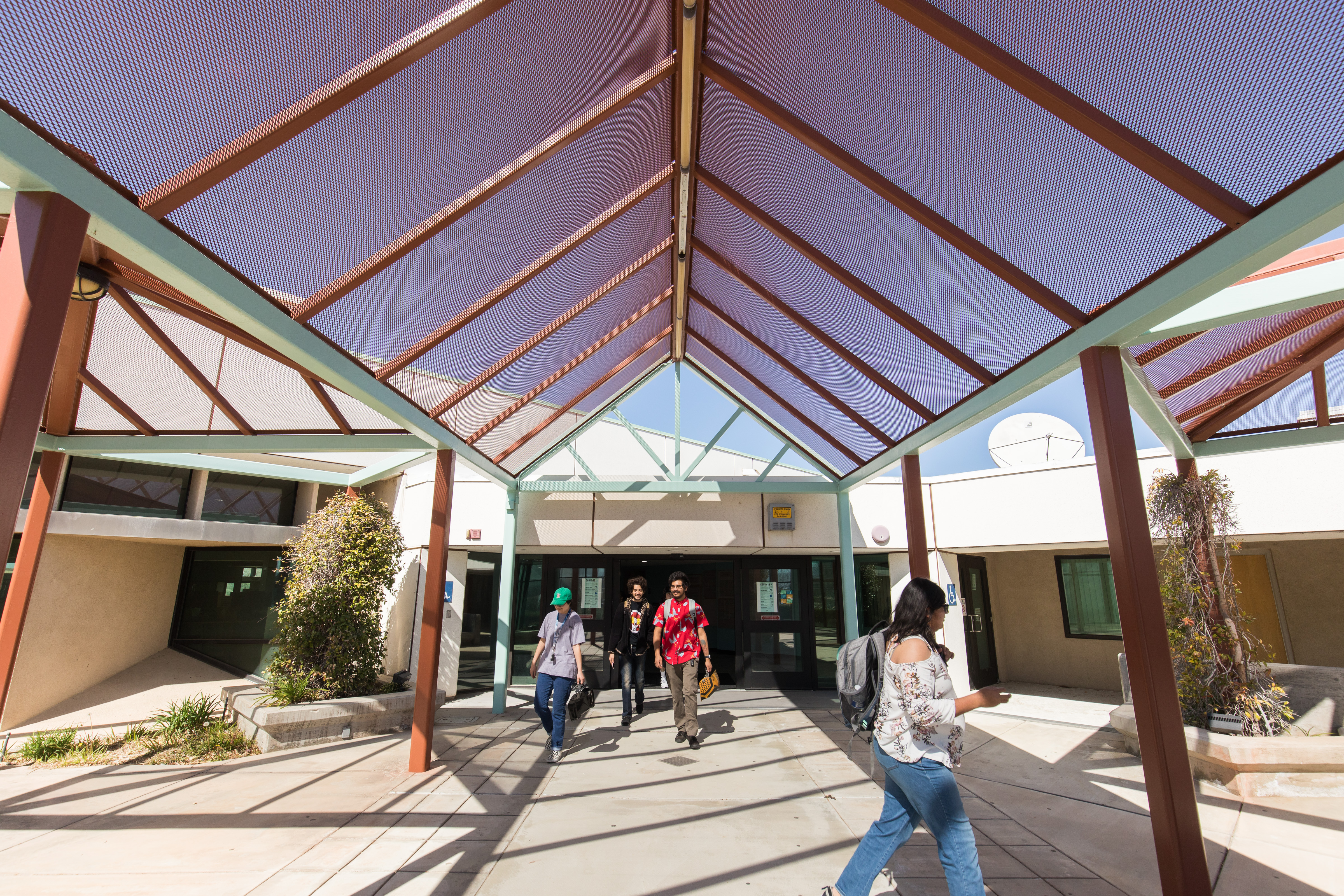 Four students walking in front of the VVC library. 